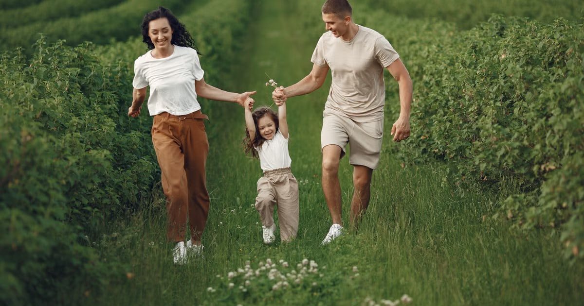 Joyful family enjoying a fun day outdoors in a green field, epitomizing togetherness and happiness.
