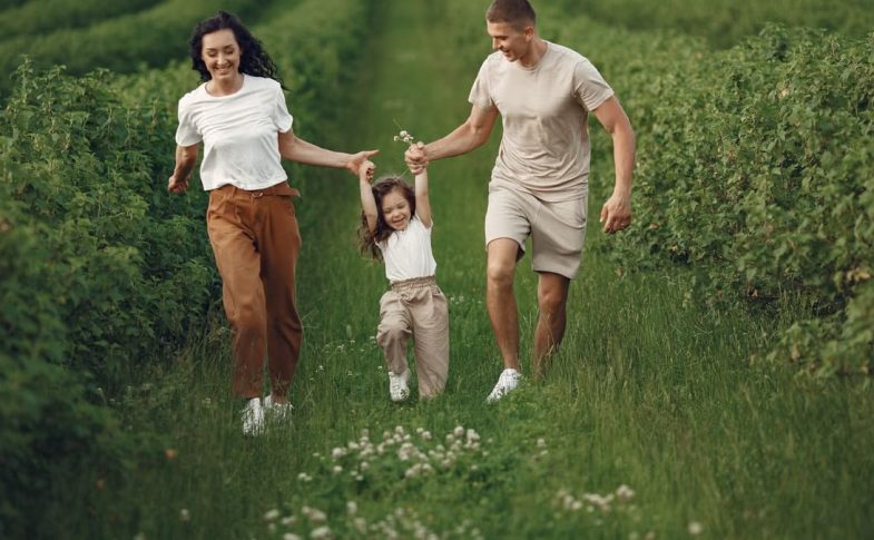 Joyful family enjoying a fun day outdoors in a green field, epitomizing togetherness and happiness.